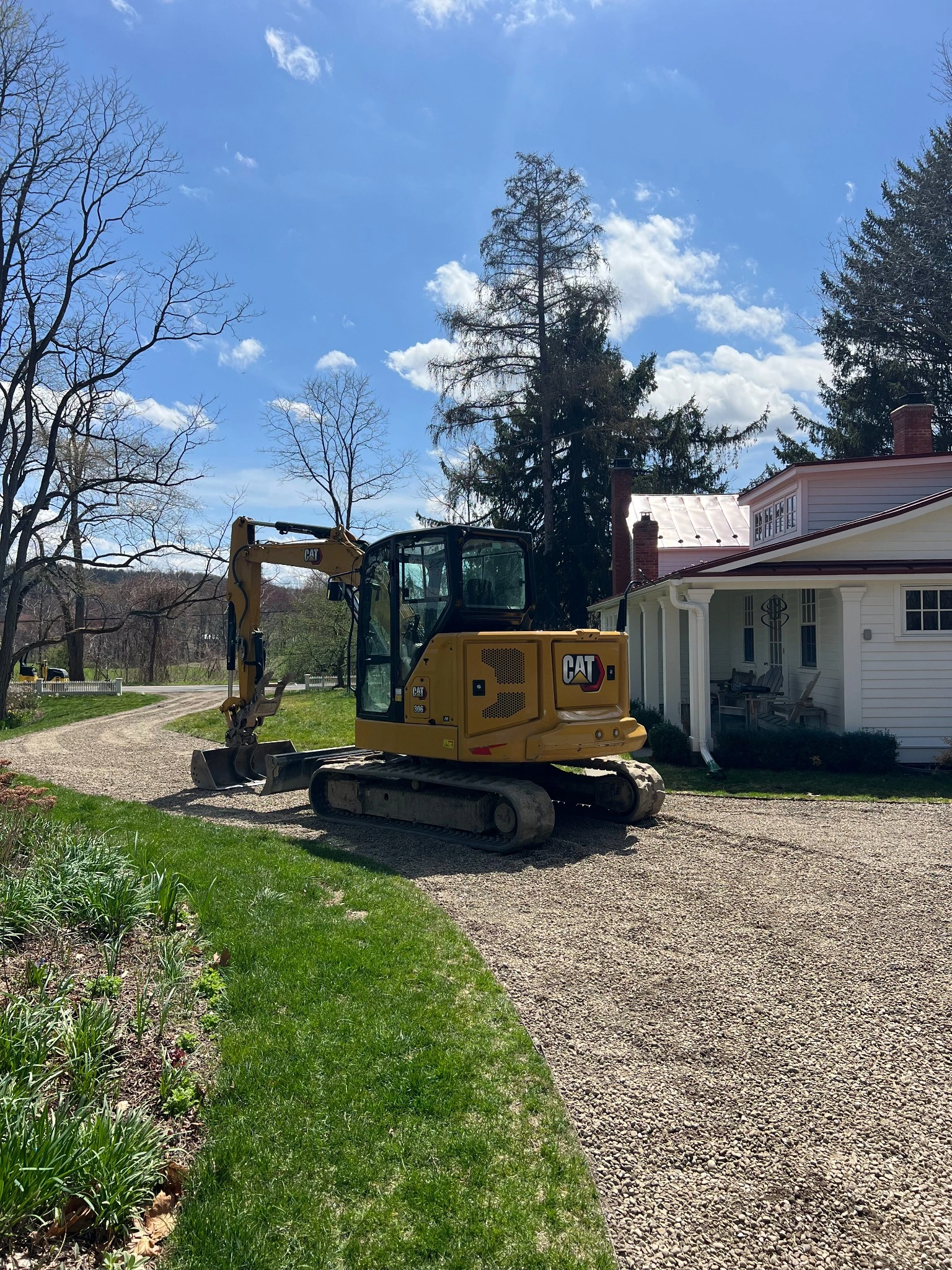 Excavator working near residential driveway and house
