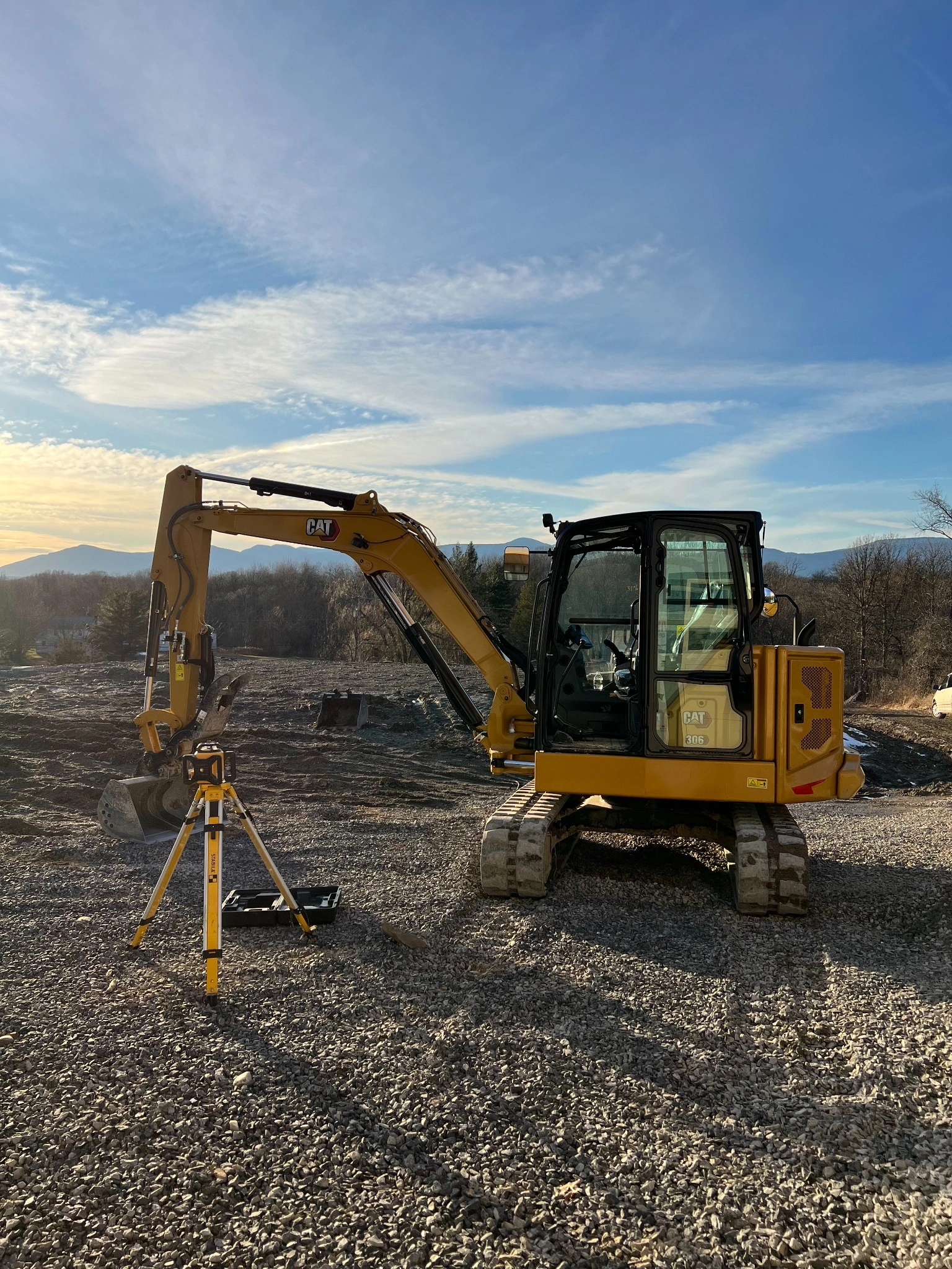 Excavator with laser level tripod for site layout